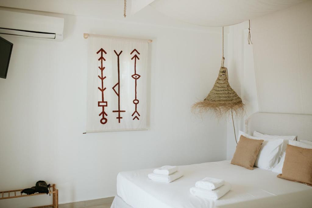 ein Schlafzimmer mit einem weißen Bett und einem Bild an der Wand in der Unterkunft Aloe Comfort House by KHI in Kythnos