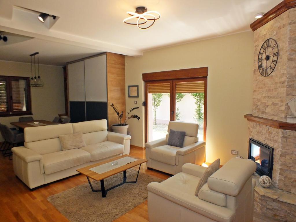 a living room with white furniture and a fireplace at Nika's House Trosobna kuća sa trpezarijom i kuhinjom,u skopu jos dva apartmana,bazen,terasa i sauna in Palić