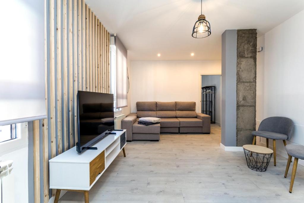 ein Wohnzimmer mit einem Sofa und einem TV in der Unterkunft BaruHaus Estrella Mansilla in Mansilla de las Mulas