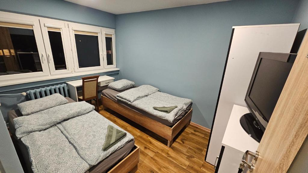 une petite chambre avec deux lits et une télévision à écran plat dans l'établissement Noclegi w Łodzi, Komfortowe Pokoje, Wielkopolska 39, à Łódź