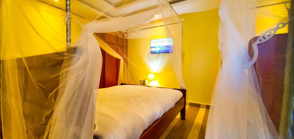 a bedroom with a canopy bed with a wedding veil at Armaflex Hotel Lira in Lira