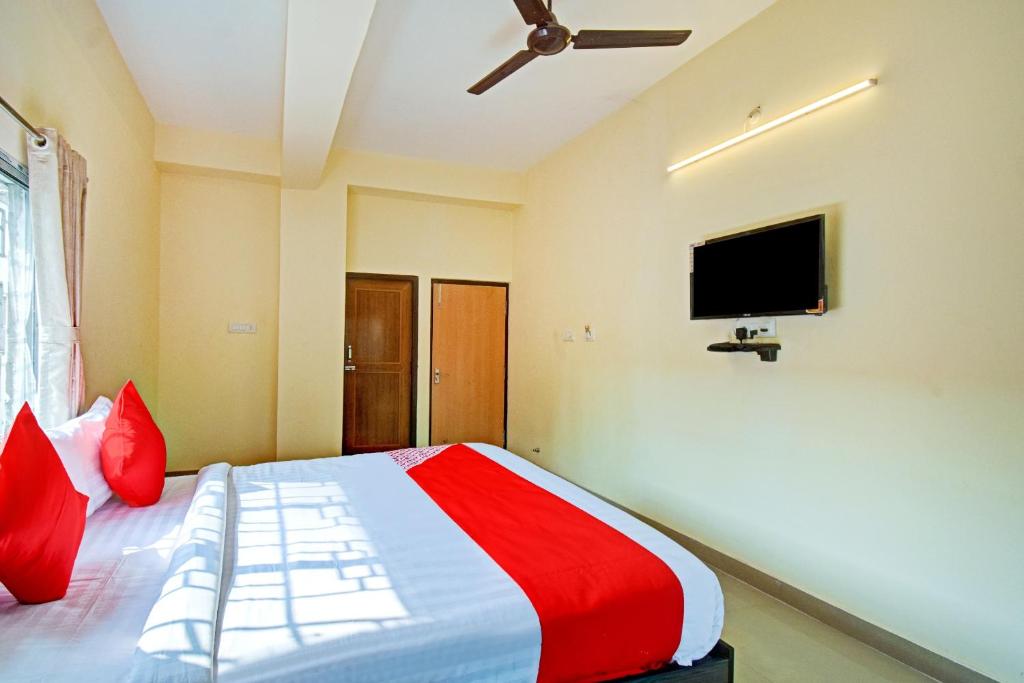 1 dormitorio con 1 cama con almohadas rojas y TV de pantalla plana en OYO Flagship Oblivion Stays en Bālihāti