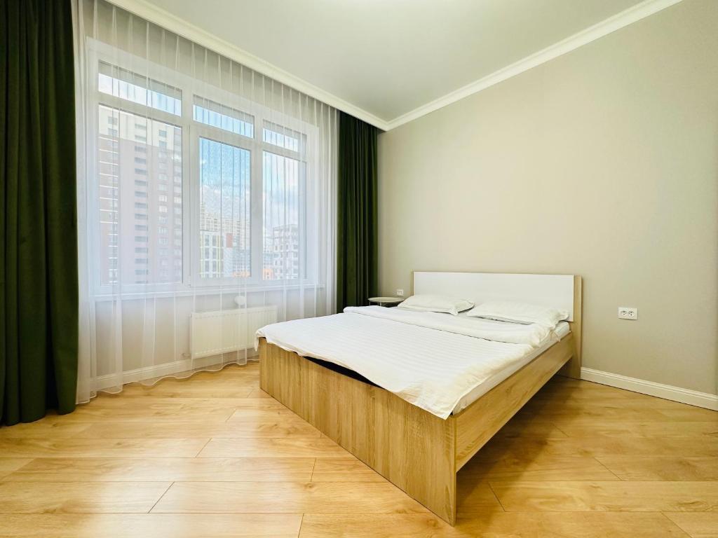Bett in einem Zimmer mit einem großen Fenster in der Unterkunft Grand Turan Comfort Two-Room Apartments in Astana