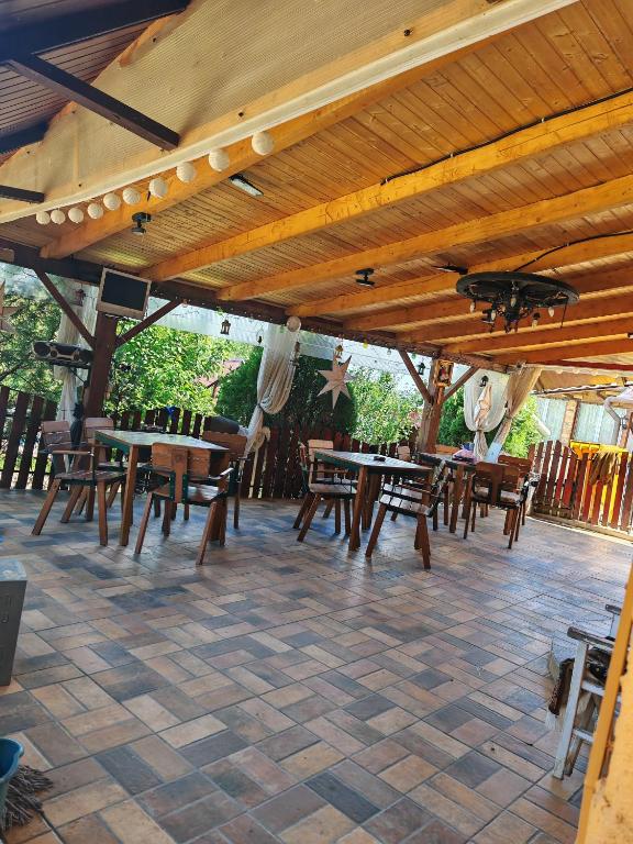 a group of tables and chairs under a wooden roof at La Popica in Tîrnăveni