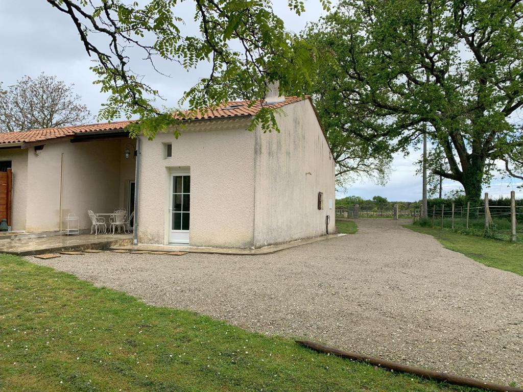 um pequeno edifício branco com uma árvore e uma entrada em Maison avec jardin privatif Gîte les Chênes de Pastouret, Lussan em Ordonnac