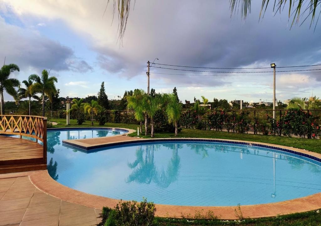 une grande piscine bleue avec une terrasse en bois dans l'établissement Village Novo Barra do Jacuípe, à Camaçari