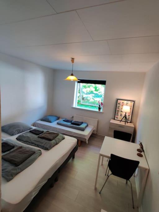 Habitación con 2 camas, mesa y ventana en Lille hyggelig centrum lejlighed! No17, en Billund