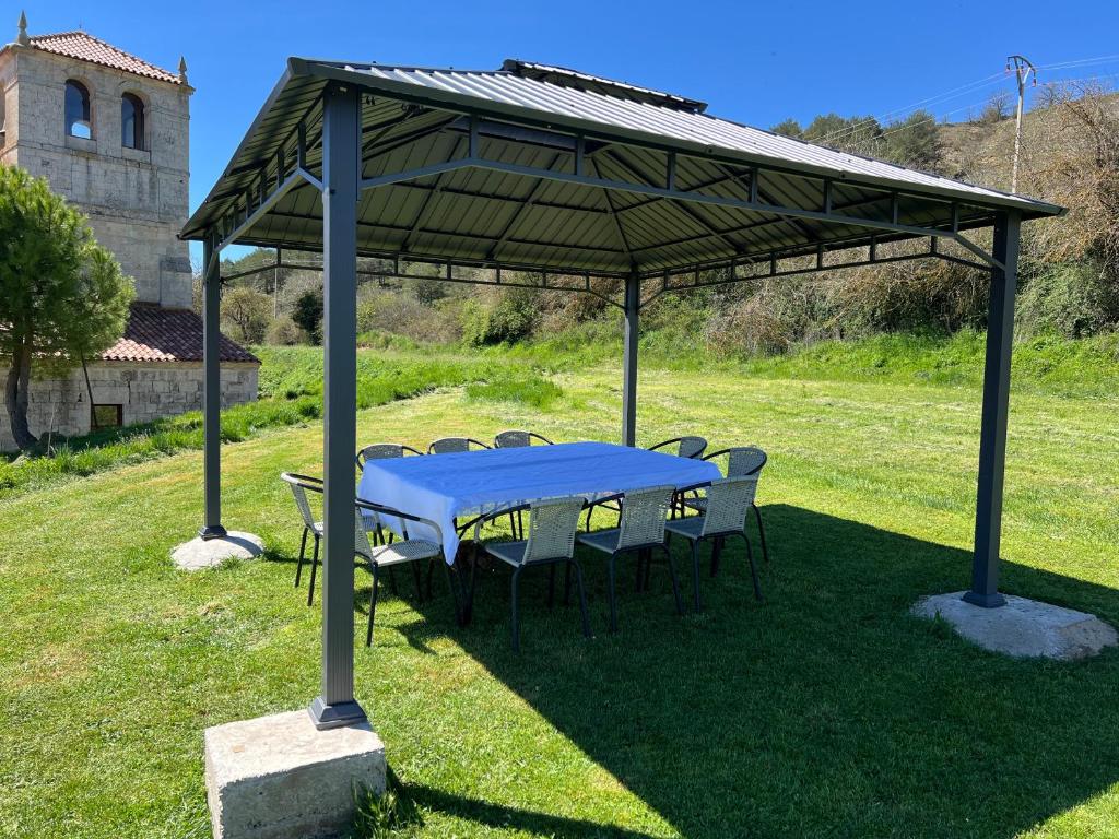 a blue table and chairs under a pavilion in a field at El Pecu Casa Rural in Bustillo del Páramo