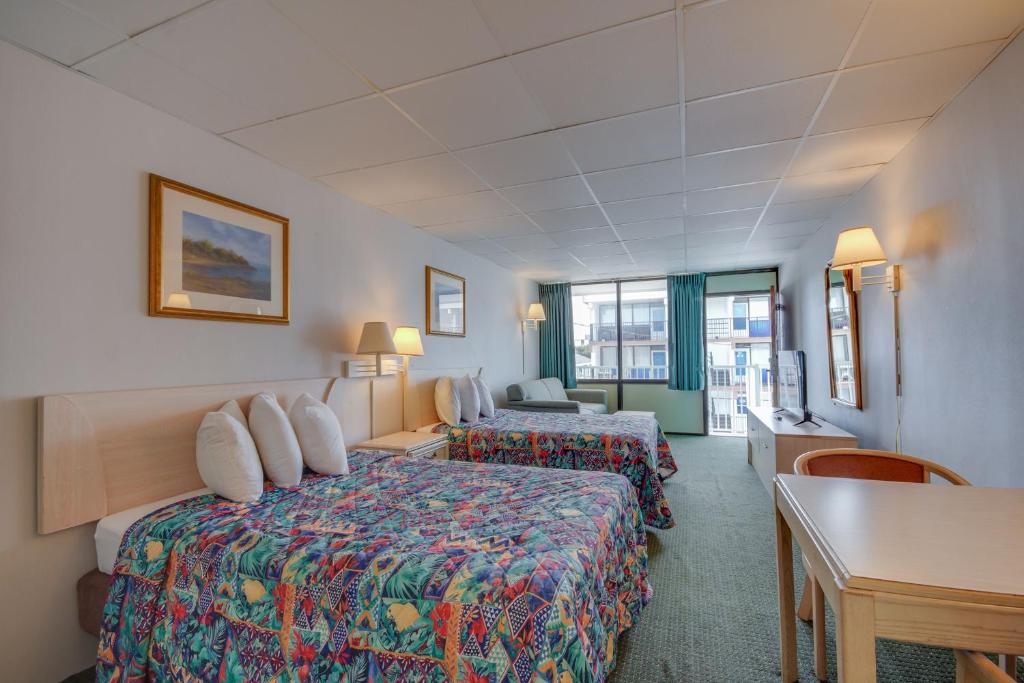 ein Hotelzimmer mit 2 Betten und einem Tisch in der Unterkunft Surf Inn Suites in Ocean City
