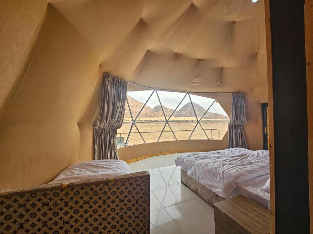 1 dormitorio con 2 camas y ventana grande en star's bubble tents, en Wadi Rum