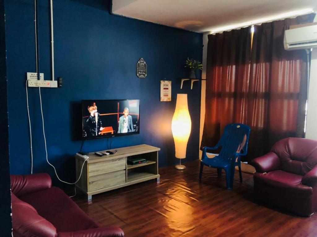 a living room with a tv and a blue wall at NR Guest House in Kangar