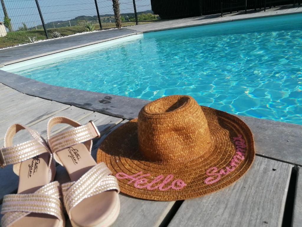 un chapeau de paille et une paire de sandales au bord d'une piscine dans l'établissement Les Lodges du Bousquet, à Tamniès