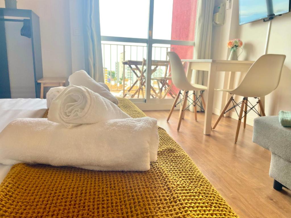 Una habitación con una cama con toallas blancas. en LUXURY SUITES MINERVA beach en Benalmádena