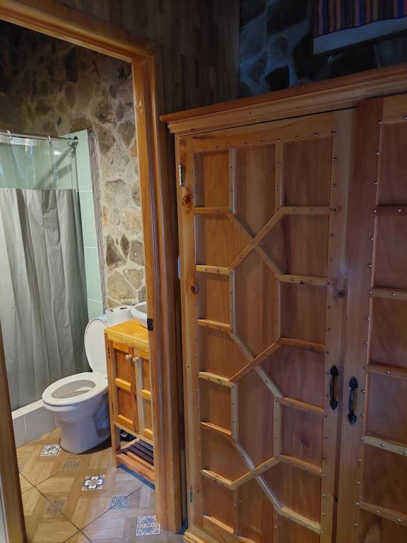 La salle de bains est pourvue d'une porte en bois et de toilettes. dans l'établissement CASA TRIBU Family room, à San Antonio Palopó