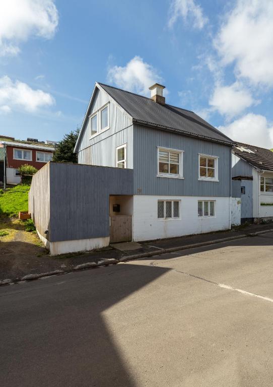 a large white house with a garage next to a street at Charming 2BR Retreat in Vestmanna in Vestmanna