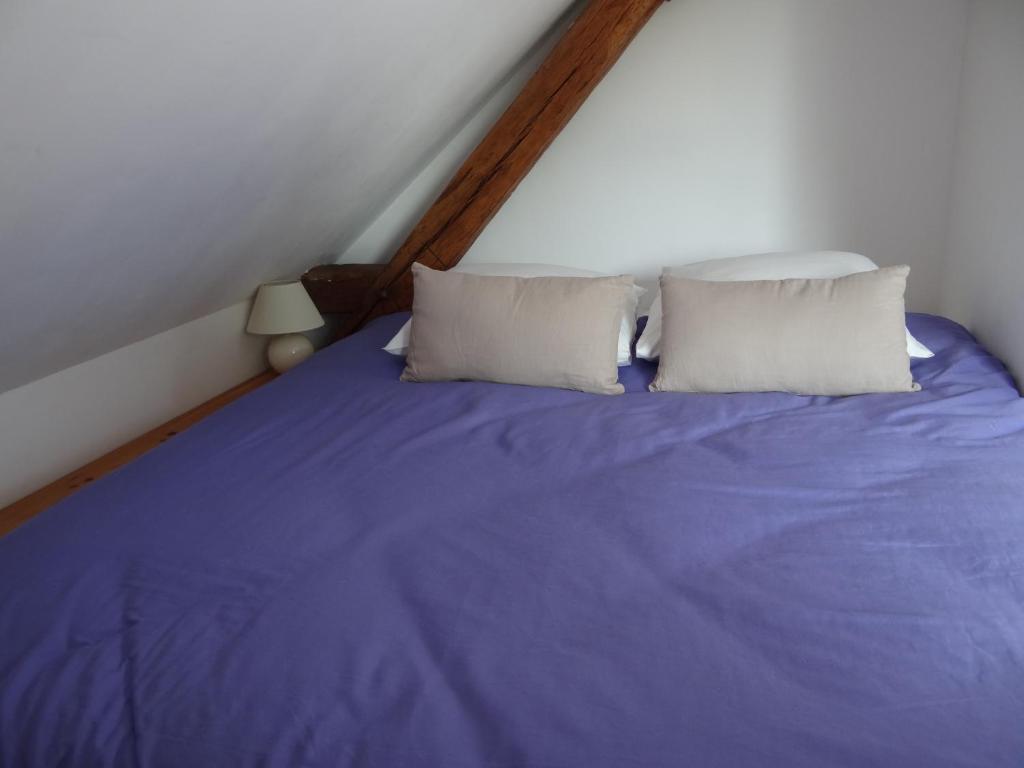 een bed met blauwe lakens en 2 kussens bij Au Moulin Géant in Rochefort-sur-Loire