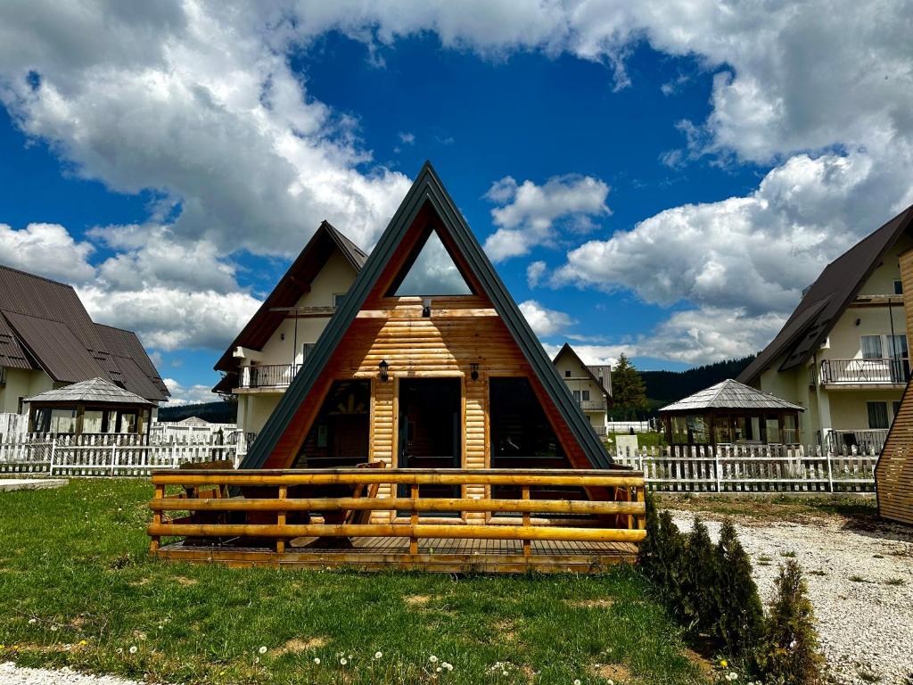 a cabin with a triangular roof in a yard with houses at Microcastl in Vlasic