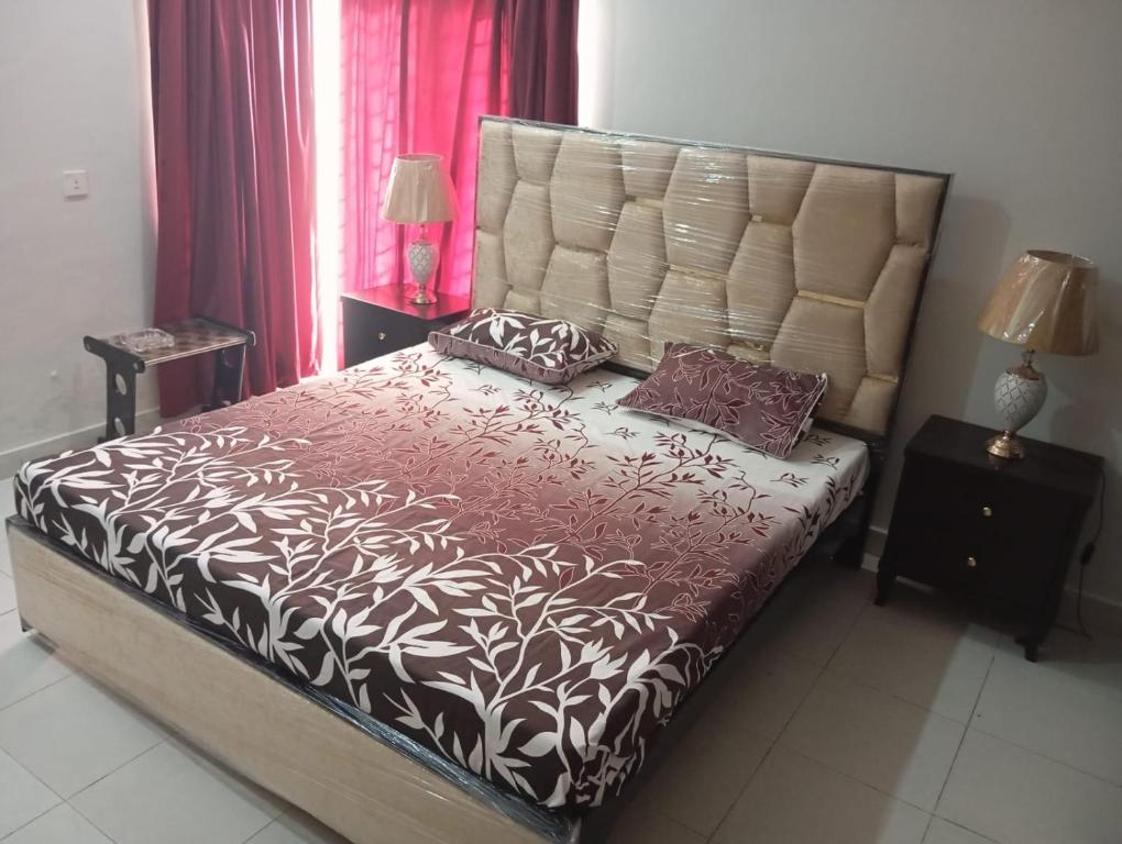 1 dormitorio con 1 cama grande y cabecero grande en Balqees Cottage en Lahore