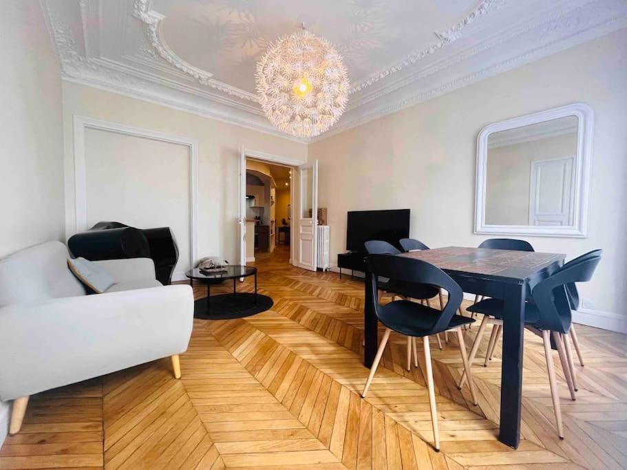 - un salon avec une table, des chaises et un lustre dans l'établissement Appart d'exception Quai de seine, à Paris
