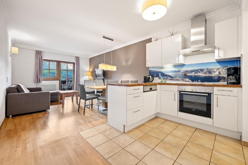 eine Küche mit weißen Schränken und ein Wohnzimmer in der Unterkunft Apartment Select TOP 8 - by Four Seasons Apartments in Piesendorf