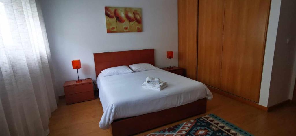 a bedroom with a bed and two night stands with lamps at Jardiv's Apart in Ponta Delgada