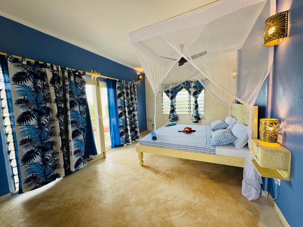 ワタムにあるOcean zuri villaの青い壁のベッドルーム1室(天蓋付きベッド1台付)