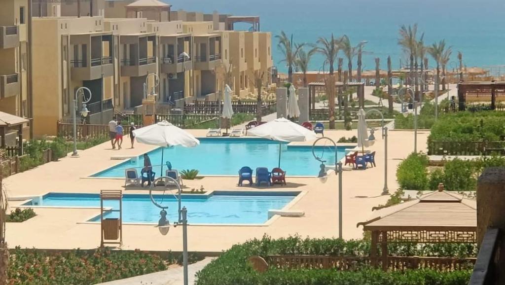 einen Pool in einem Resort mit Palmen und Gebäuden in der Unterkunft Tavira شاليه in Ras Sudr