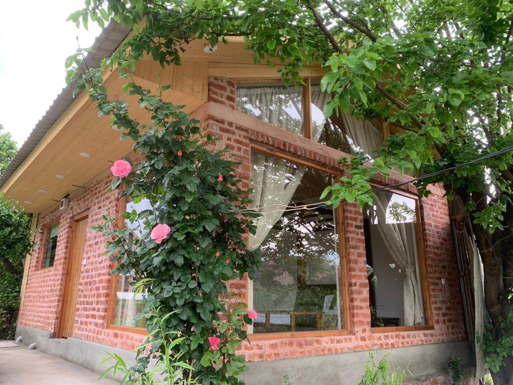 ein Backsteinhaus mit einem großen Fenster mit rosa Rosen in der Unterkunft Nigeen Vista Lakeside Chalet in Srinagar