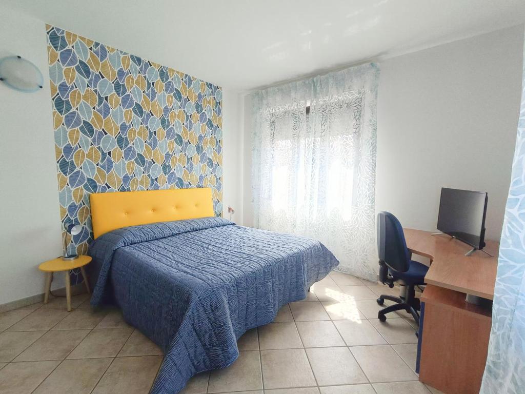 a bedroom with a bed and a desk and a television at Affittacamere Center Room in Tortolì