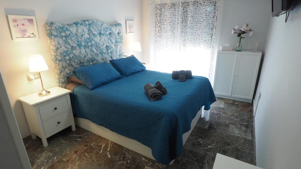 Un dormitorio con una cama azul con un par de zapatos. en Bonito apartamento en centro ciudad con garaje, en Albacete
