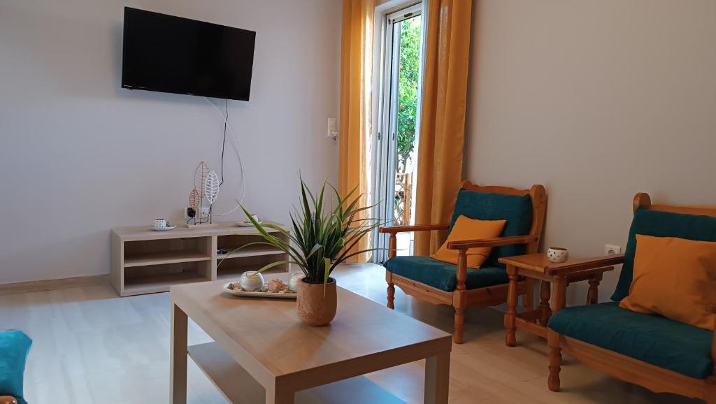 uma sala de estar com cadeiras, uma mesa e uma televisão em Katerina Holiday House em Anavissos