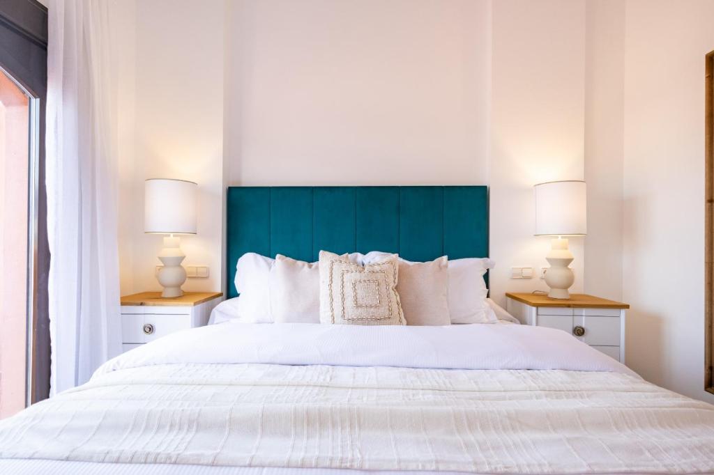 a bedroom with a large white bed with two lamps at Increíble y Moderno apartamento Duplex con piscinas y preciosas vistas in Estepona