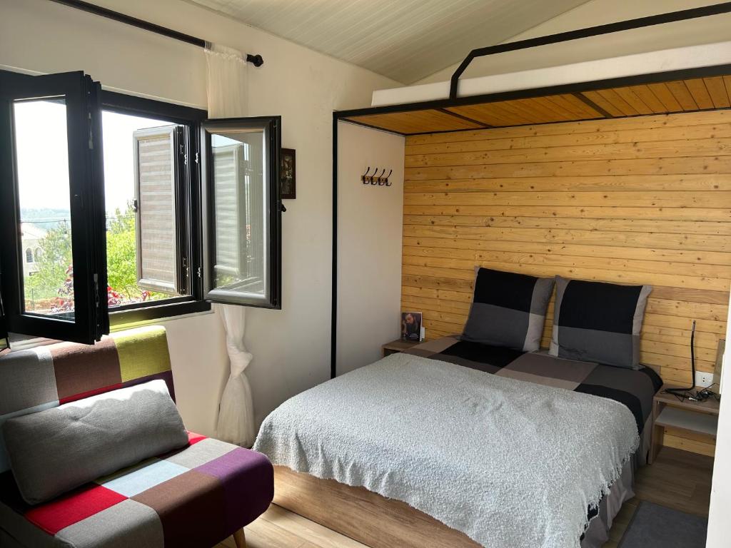 Un dormitorio con una cama y dos ventanas y una silla. en Casa del mir, en Dayr al Qamar