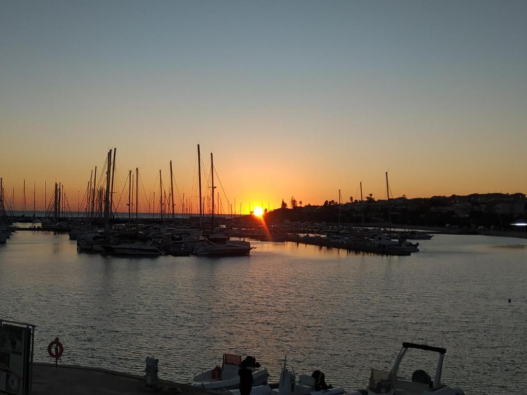 einen Sonnenuntergang über einem Jachthafen mit Booten im Wasser in der Unterkunft Domus Maregi in Marina di Ragusa