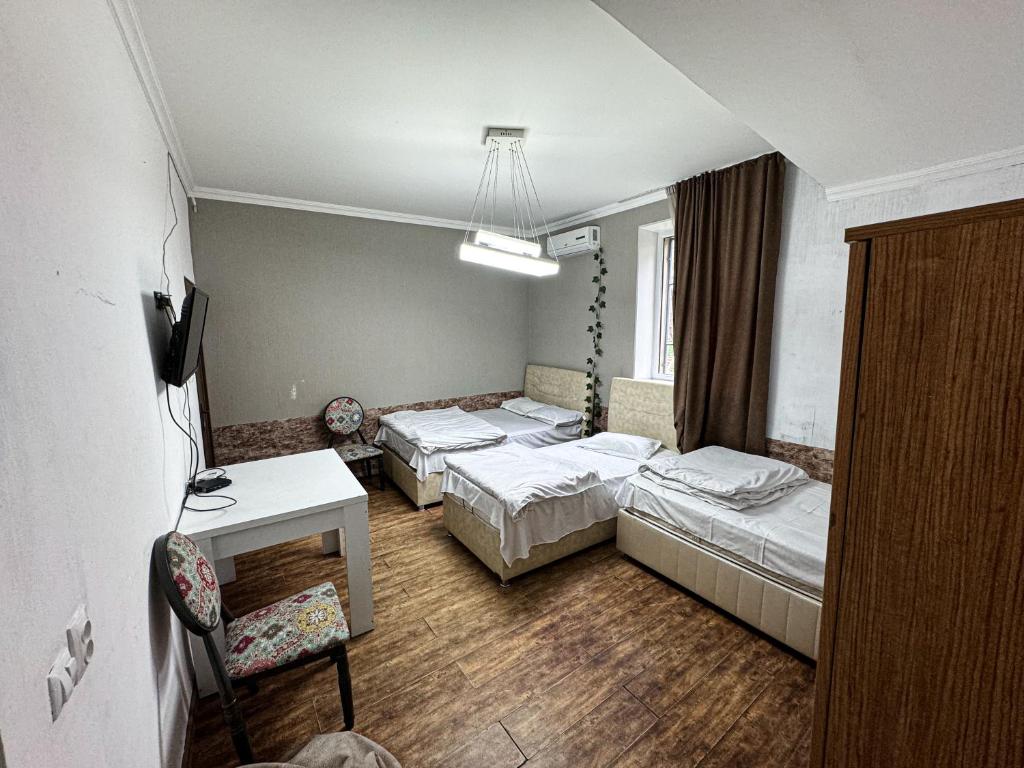 a room with three beds and a table and a desk at kessane in Akhaltsikhe