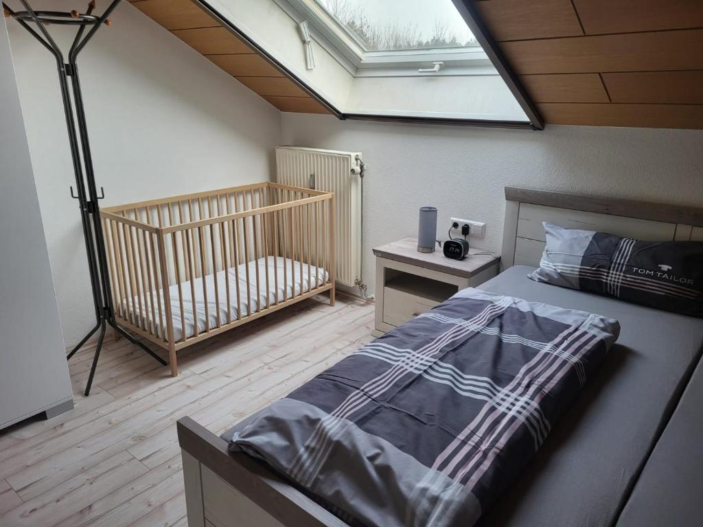 una camera da letto con un letto e una culla con un lucernario di Schweizer´s Ferienwohnung ad Achberg