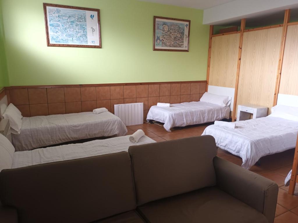 a room with three beds and a couch in it at A CONDA in Arzúa