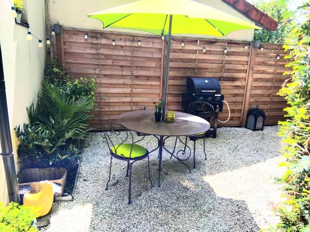 une table et des chaises avec un parasol et un grill dans l'établissement Le cosy de Noisy, à Noisy-le-Sec