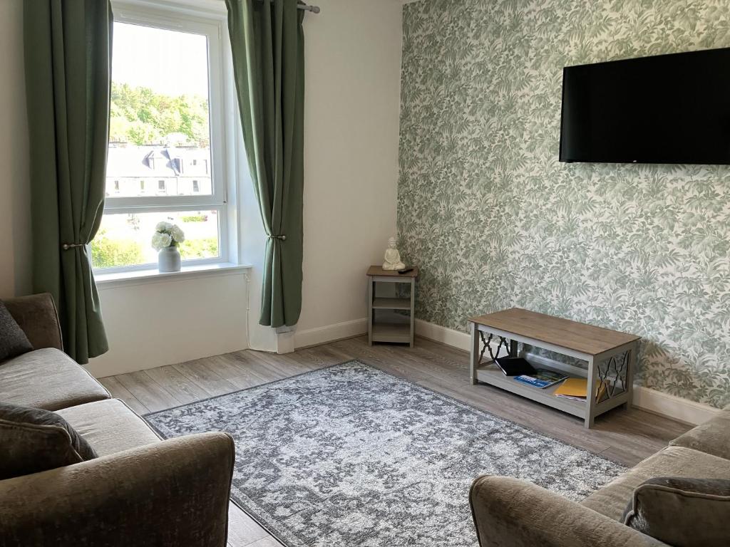 een woonkamer met een bank en een tv aan de muur bij River View in Hawick