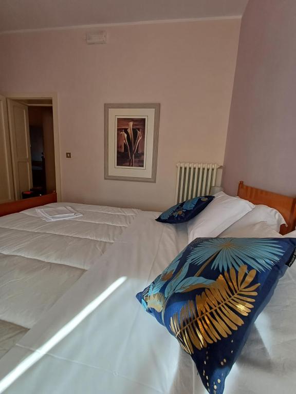 Alloggio Taddei في Barisciano: سريرين بيض في غرفة نوم مع صورة على الحائط
