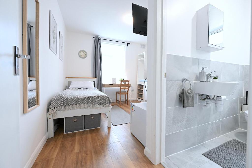 uma casa de banho branca com um lavatório, um WC e um espelho. em Studio Apartment - London em Londres