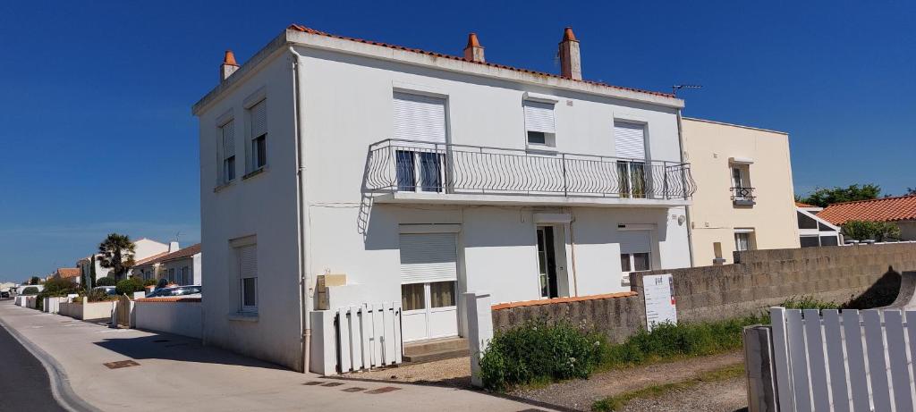 un bâtiment blanc avec une clôture devant dans l'établissement Maison avec garage proche de la plage, à Les Sables-dʼOlonne