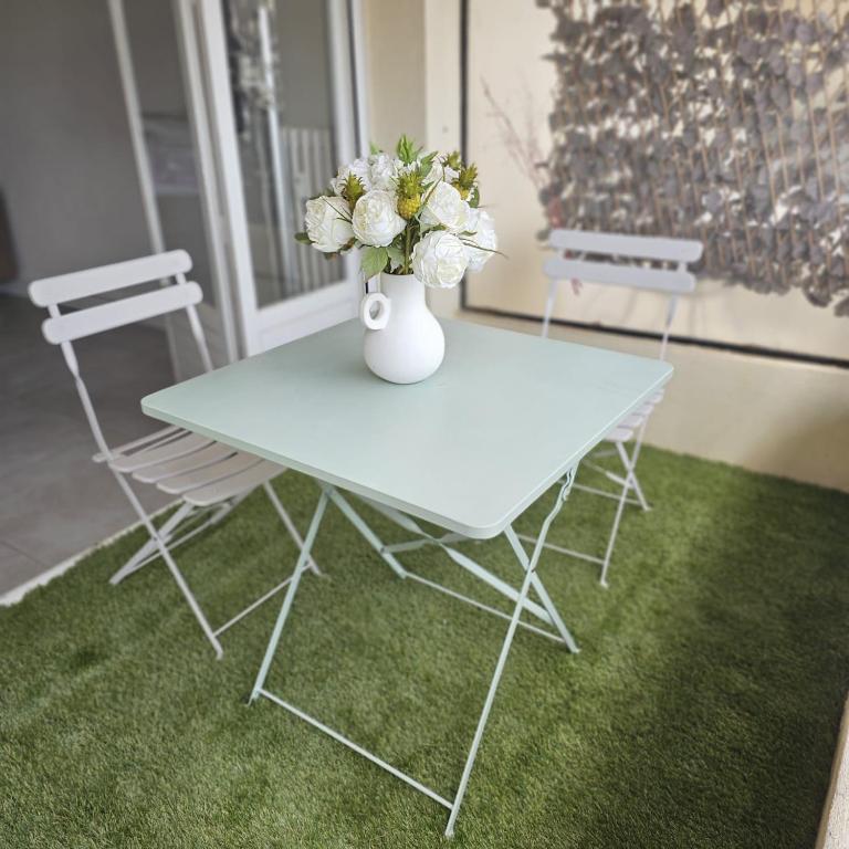 une table blanche avec un vase et des fleurs sur elle dans l'établissement Studio Cannes le Val D'or Chez Lisa, à Cannes