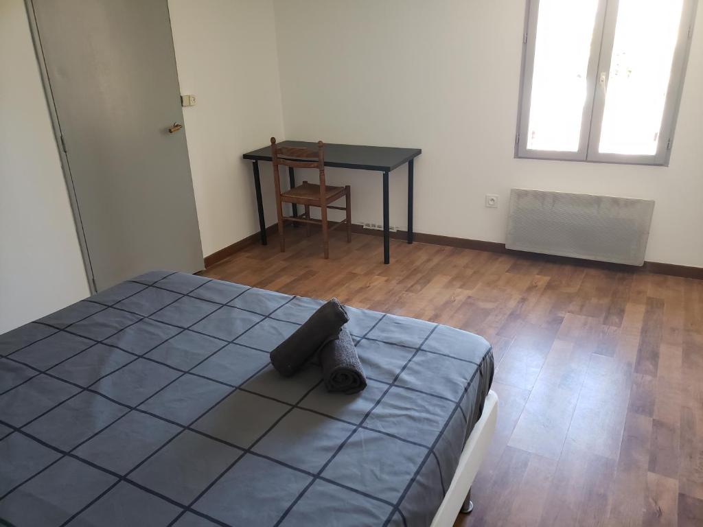 a bedroom with a bed and a table and a chair at Chambres individuelles pour courtes et moyennes durées in LʼIsle-Jourdain