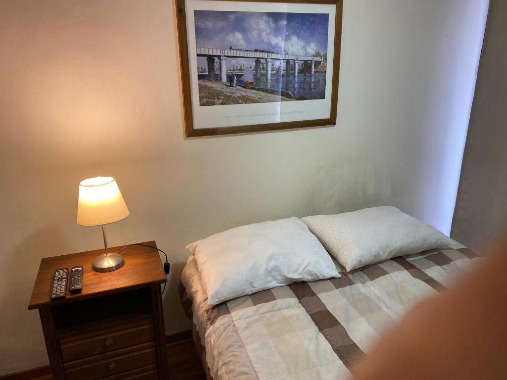 ein Schlafzimmer mit einem Bett mit einer Lampe und einem Bild an der Wand in der Unterkunft Departamento Santiago Centro - Metro Santa Lucia in Santiago