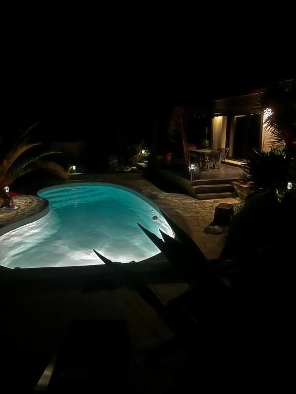 una gran piscina por la noche con un fondo oscuro en Partie de villa moderne avec piscine En option jaccuzi dans espace détente indépendant, en Villeneuve