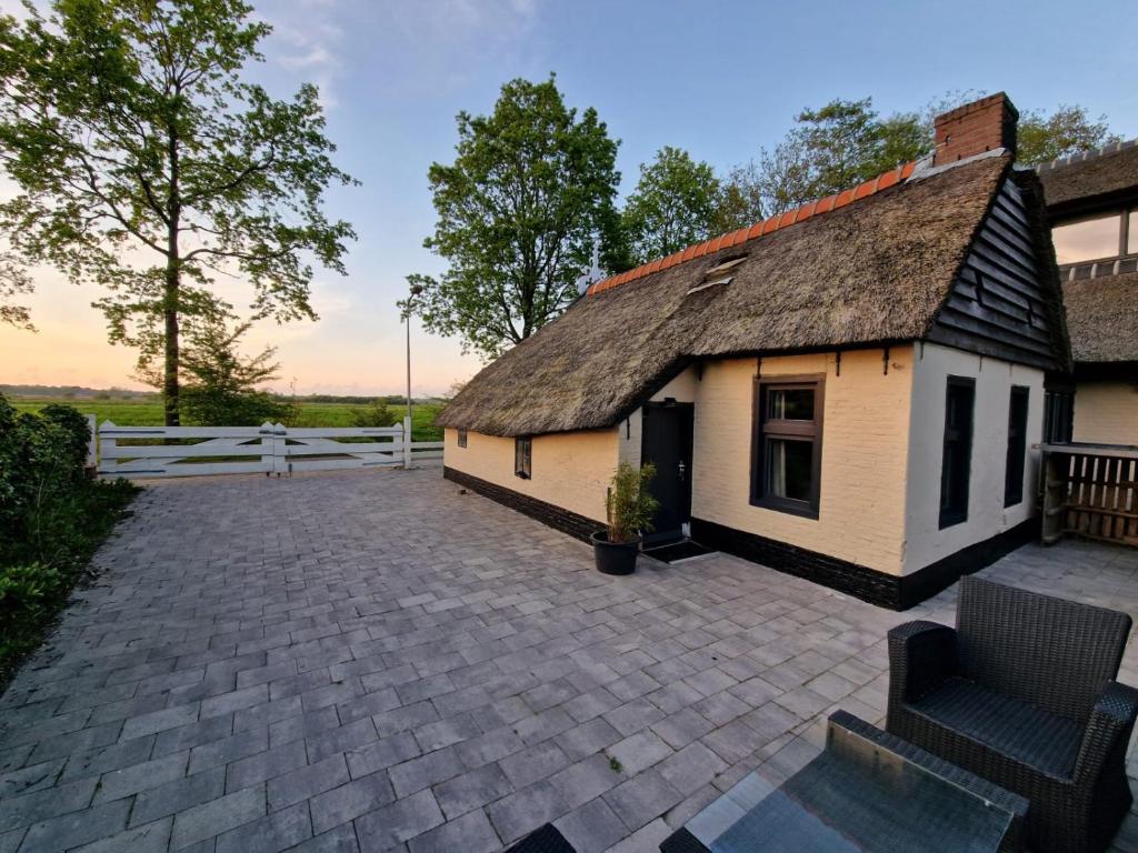 uma casa com telhado de palha e um pátio em Bed en stal 'Het Woudhuisje' em Ryptsjerk