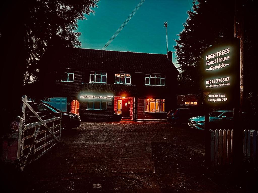 un bâtiment éclairé avec un panneau devant lui dans l'établissement High Trees Guest House Gatwick, à Hookwood