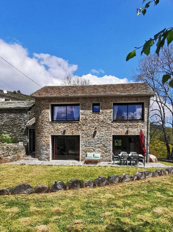 une maison en pierre avec des tables et des chaises devant elle dans l'établissement Mas du Petit Pradal, à Cassagnas