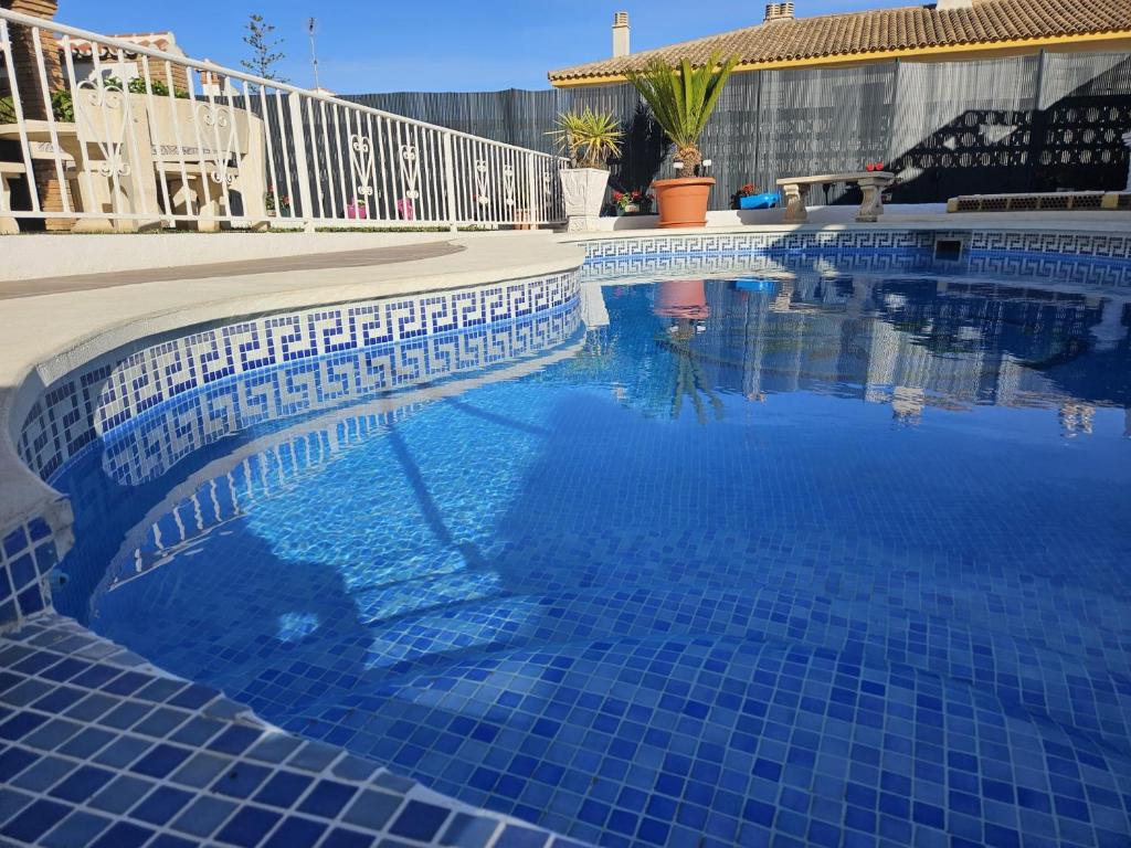 a swimming pool with a blue tile floor and a fence at Villa Tony - Benalmádena in Arroyo de la Miel